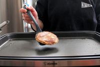 A person using the GIR Premium Silicone Mini Flipper to flip food