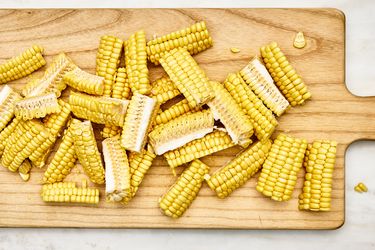 Corn cobs sliced into segments on a wooden cutting board