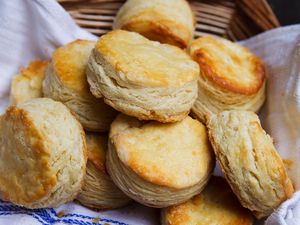 A towel-lined basket full of buttermilk biscuits. 