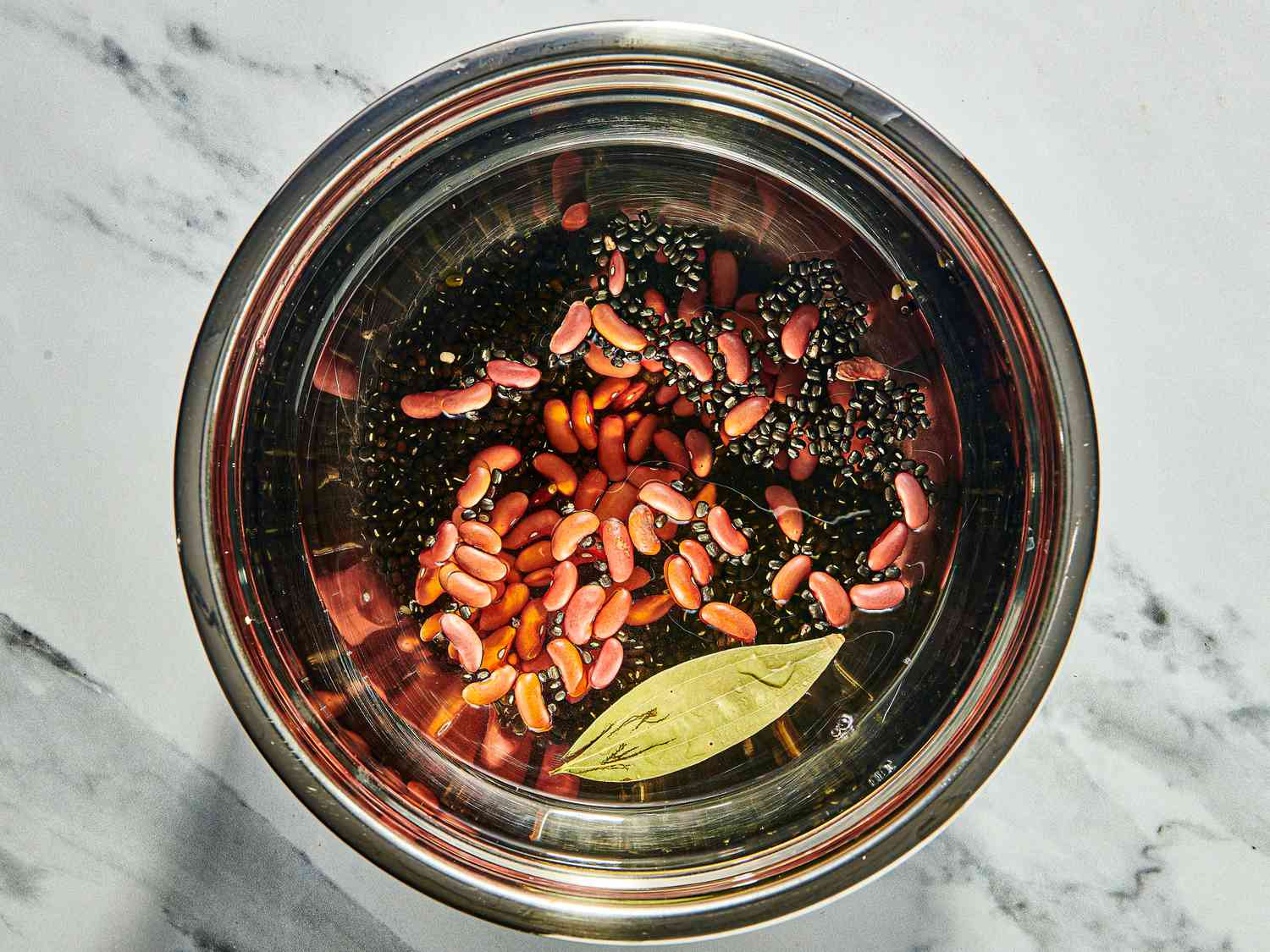 Beans and bay leaves with water in a metal bowl 