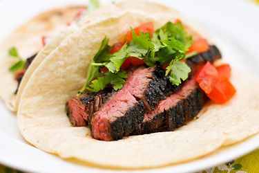Sliced skirt steak tacos with tomatoes and cilantro on a plate
