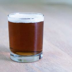 A short rocks glass of deep golden-brown altbier.