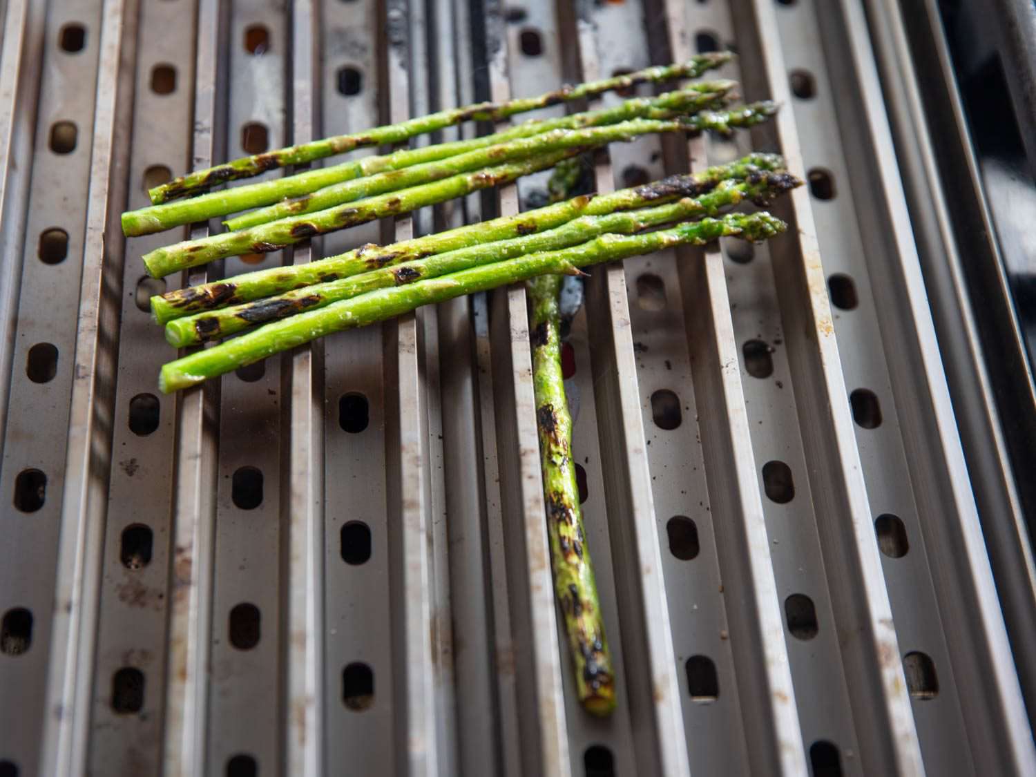 Asparagus charring on the GrillGrate; the stalks show even browning from stem to tip