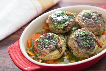 Closeup of old fashioned artichokes barigoule with mushrooms, served in an enameled casserole dish.