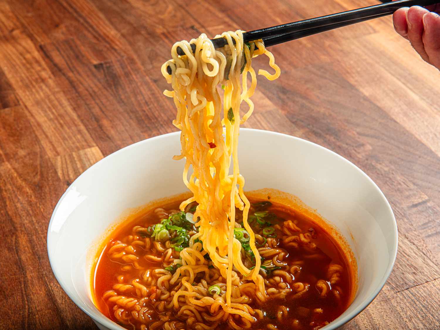 Chopsticks lifting noodles out of a bowl of soup