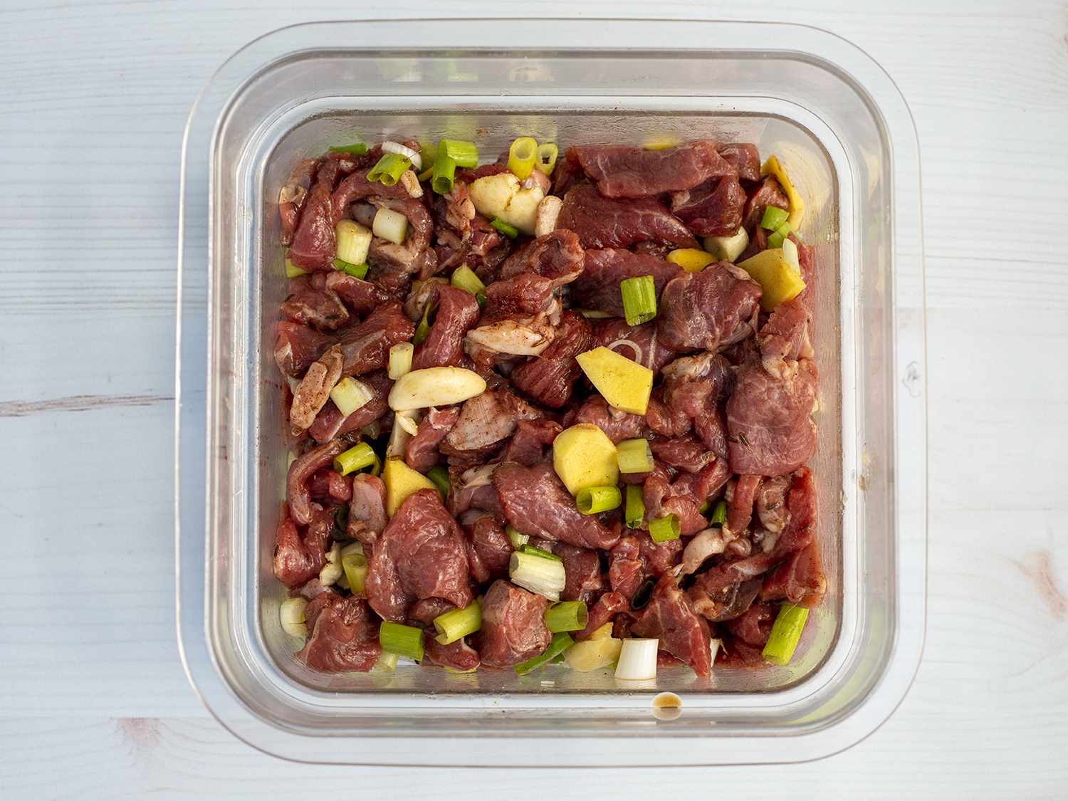 Lamb pieces marinating in a square cambro container