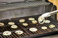 A person cooks onions on the Weber Genesis E-335 Gas Grill