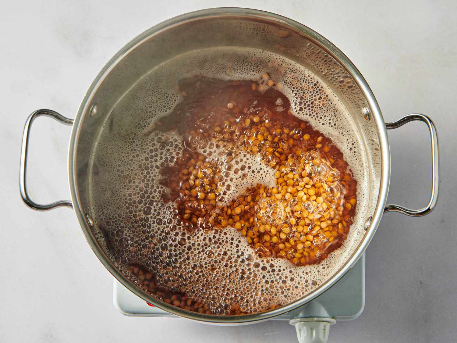 A pot containing lentils cooking on a stovetop