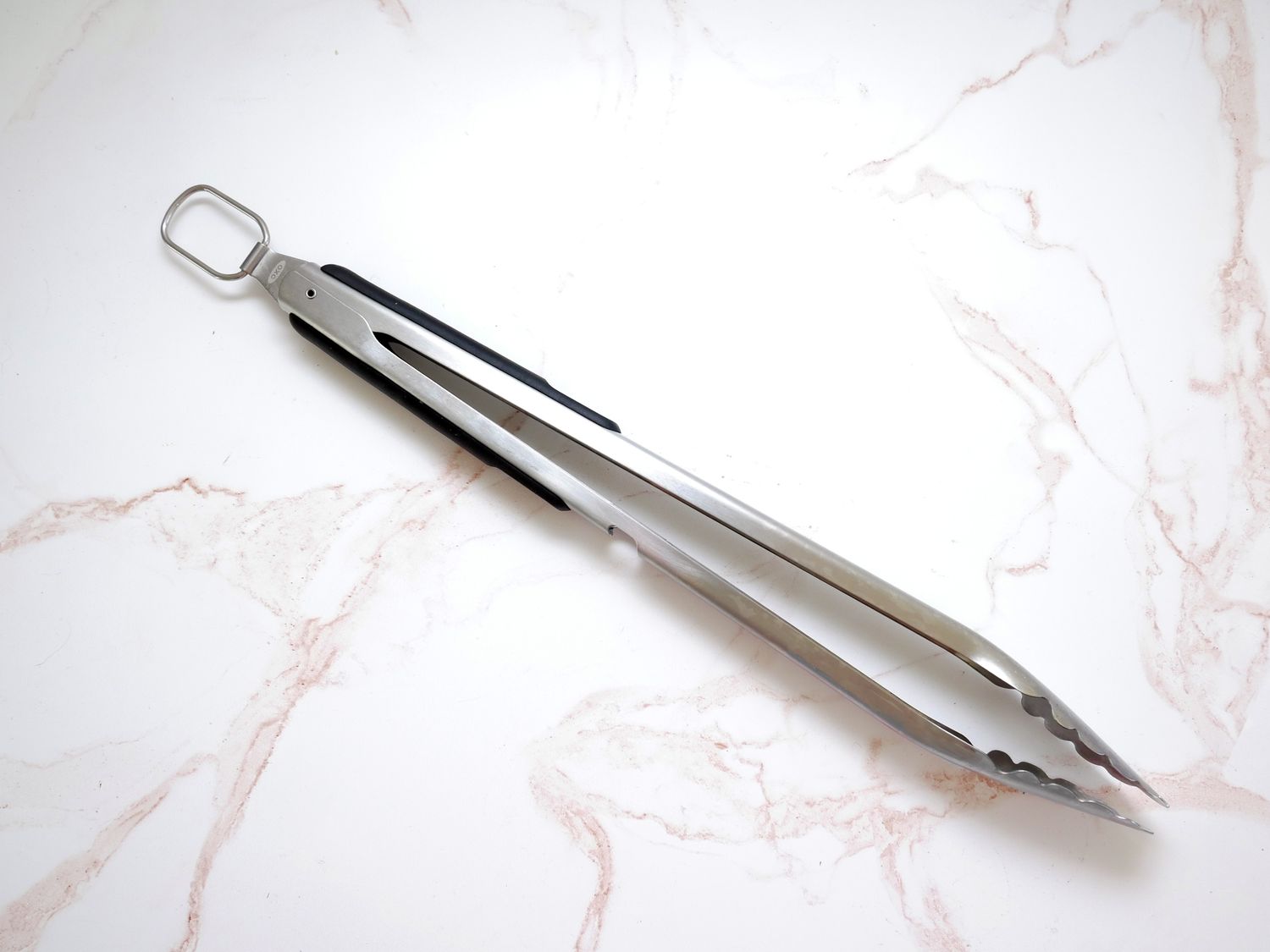 a pair of tongs on a white marble backdrop