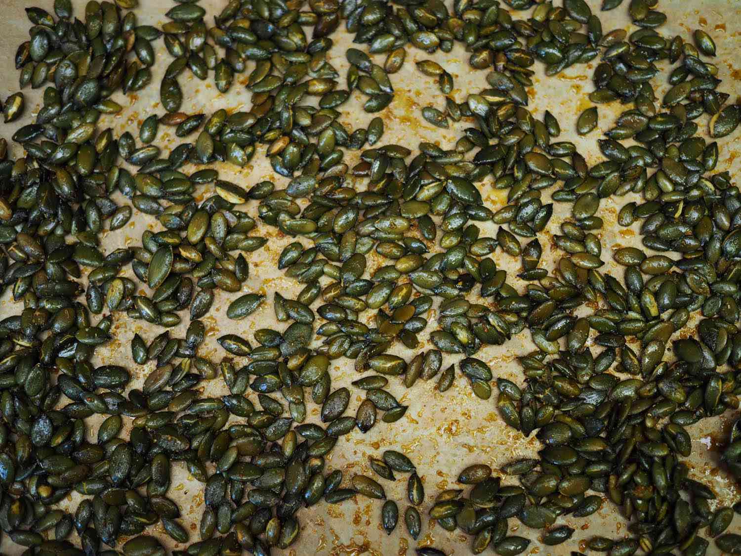 Overhead view of spiced, toasted pepitas on a sheet pan.