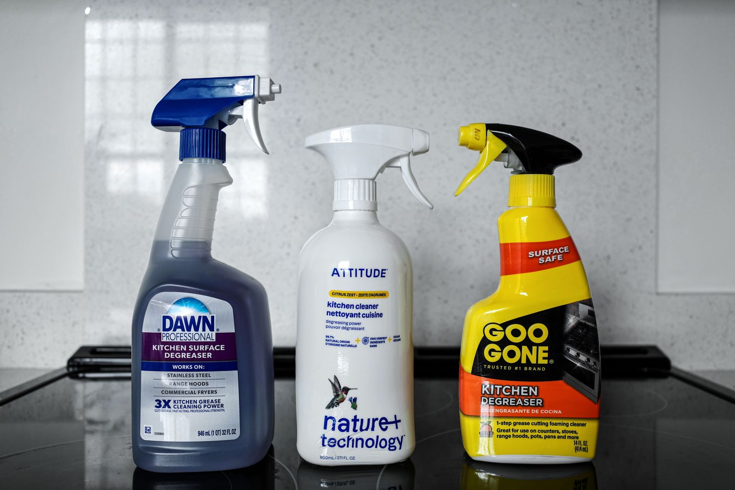 Three kitchen degreasers on a glass stovetop