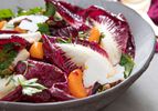 Close-up of a large ceramic salad bowl filled with dressed Trevisano radicchio, mandarin orange segments, herbs, pistachios, and ricotta salata.