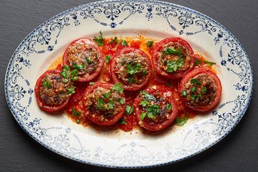A platter of Vietnamese-style pork-stuffed tomatoes garnished with herbs