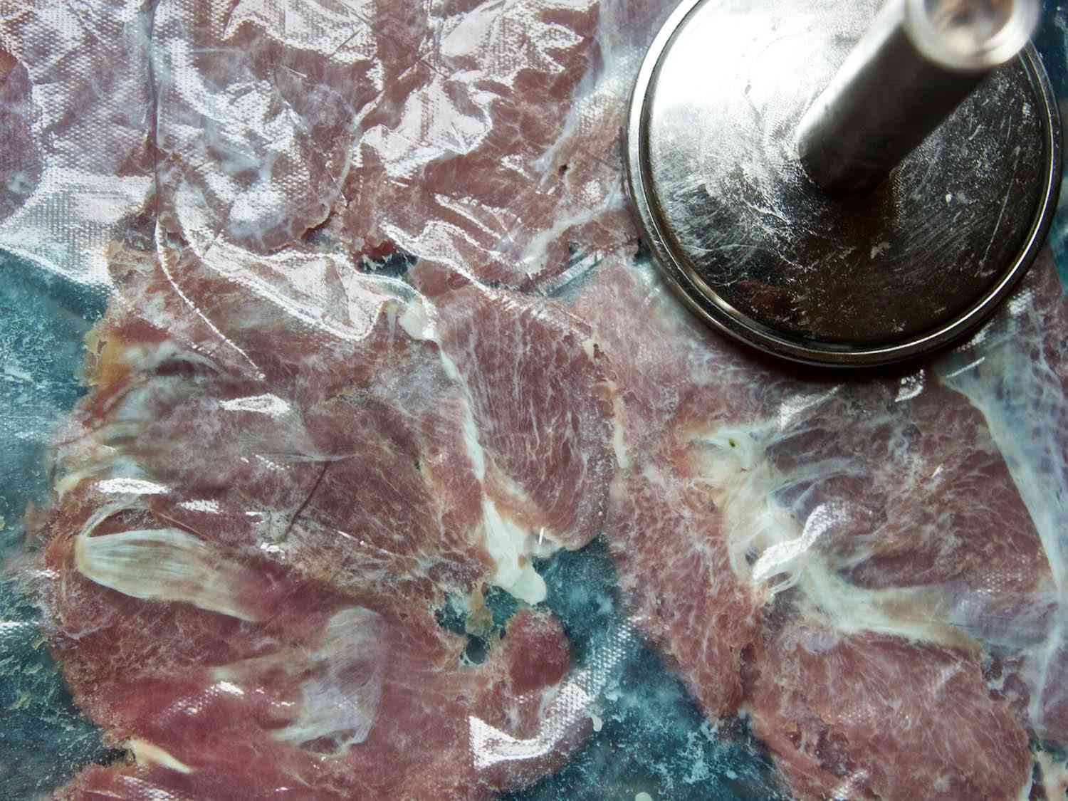 Closeup of the pieces of turkey thigh, pounded flat in a zip-top bag.