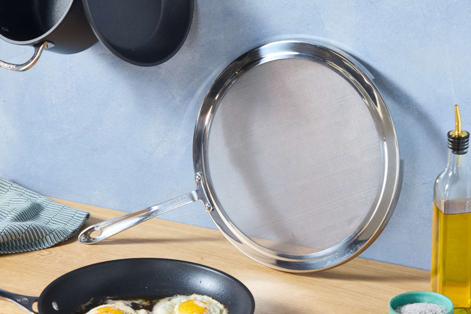 the all-clad splatter screen resting on a blue backdrop