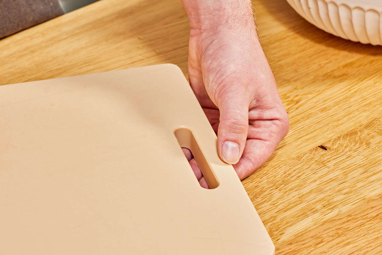 A person placing a plastic cutting board onto a countertop.