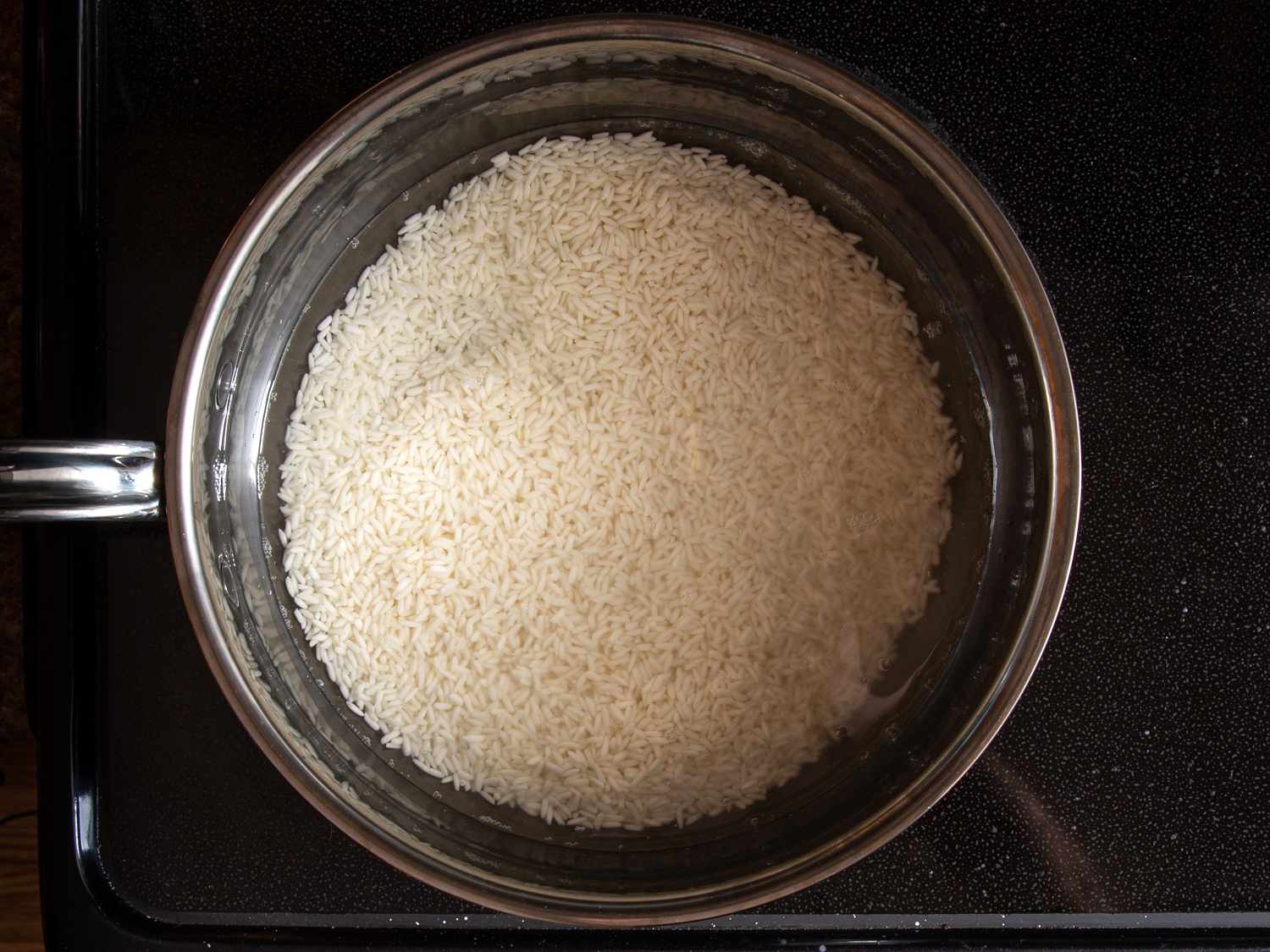 white rice in water in a pan on the stovetop