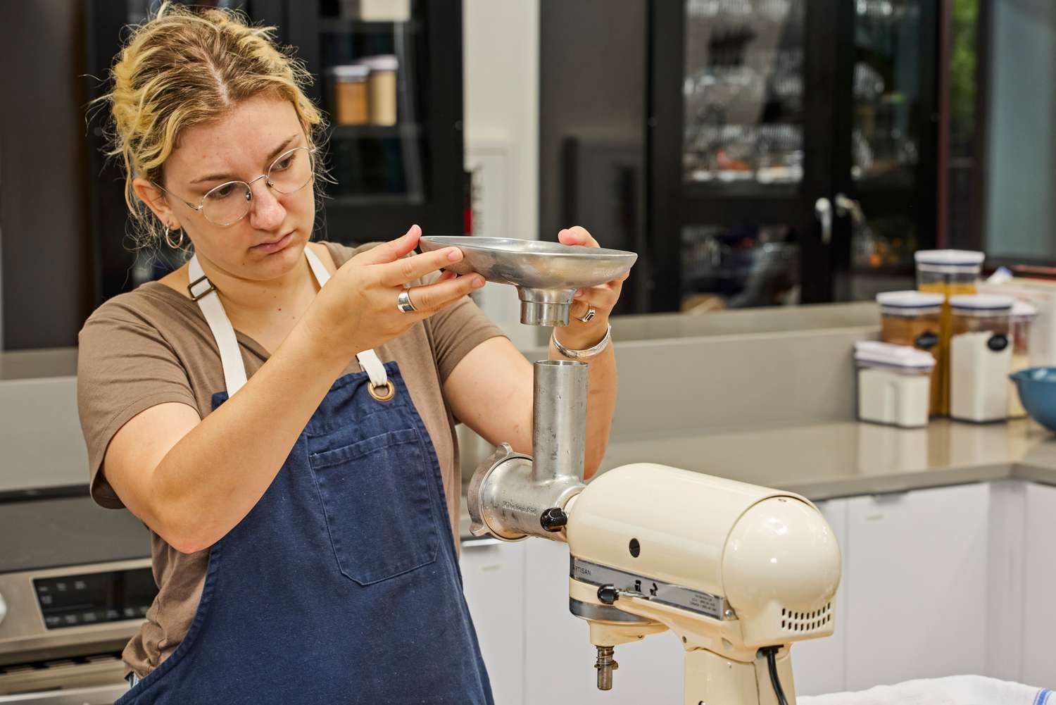 Person installing food tray of KitchenAid KSMMGA Metal Food Grinder Attachment