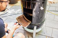 A person looks inside the Weber Smokey Mountain Cooker 18-Inch Charcoal Smoker (721001)