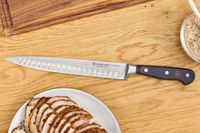 The Wüsthof Classic 9 Inch Hollow Edge Carving Knife on a cutting board