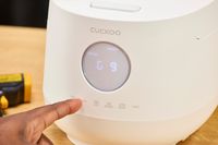 A person presses a button on the Cuckoo 6-Cup Micom Rice Cooker