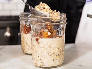 Preparing overnight oats in mason jars with oats milk and spiced apple topping