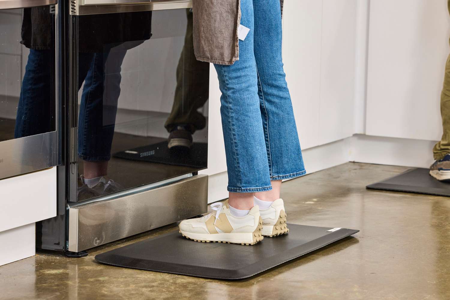 A person stands on the Sky Solutions Sky Mat 0.75-Inch Comfort Anti-Fatigue Mat in sneakers