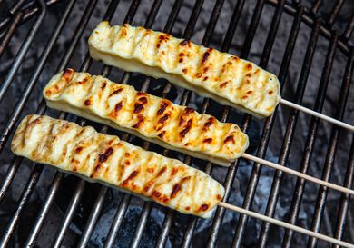 Grilled Brazilian cheese skewers on a grill grate, getting nicely browned.