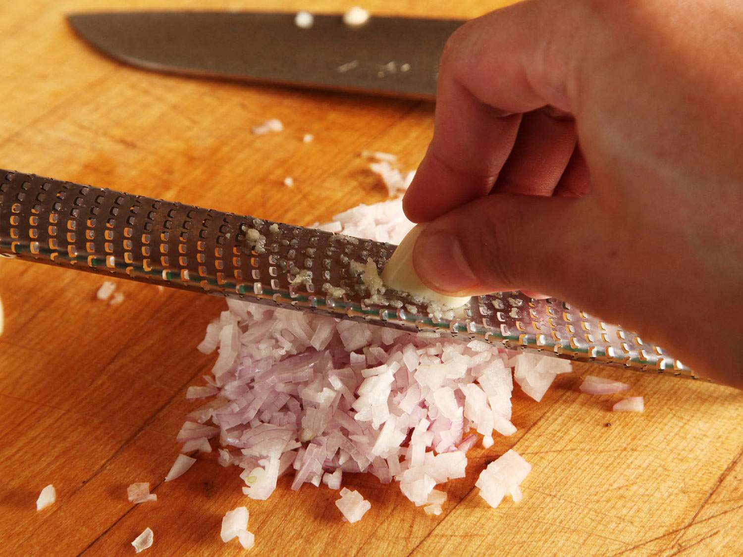 Using a microplane to grate a garlic clove.