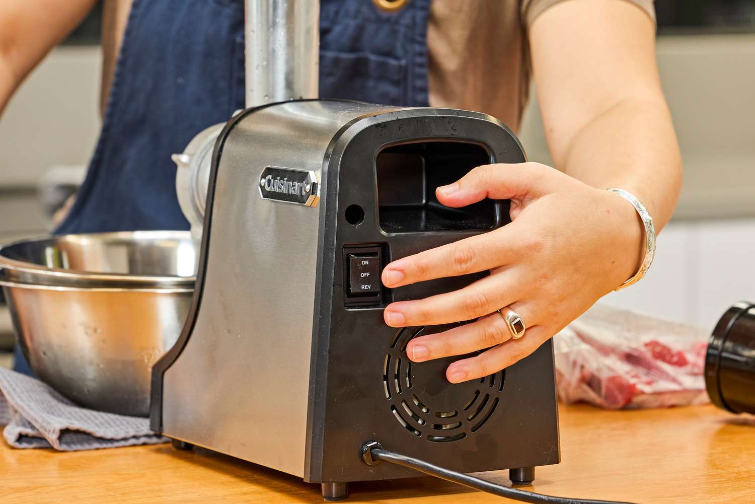 A person presses a button on the Cuisinart Electric Meat Grinder
