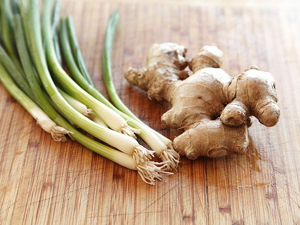 Scallions and ginger on a cutting board. 