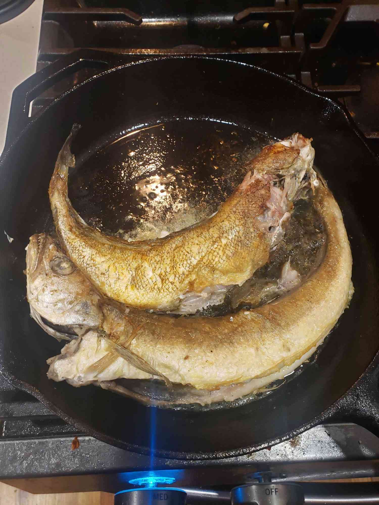 Fried whiting in a cast iron pan