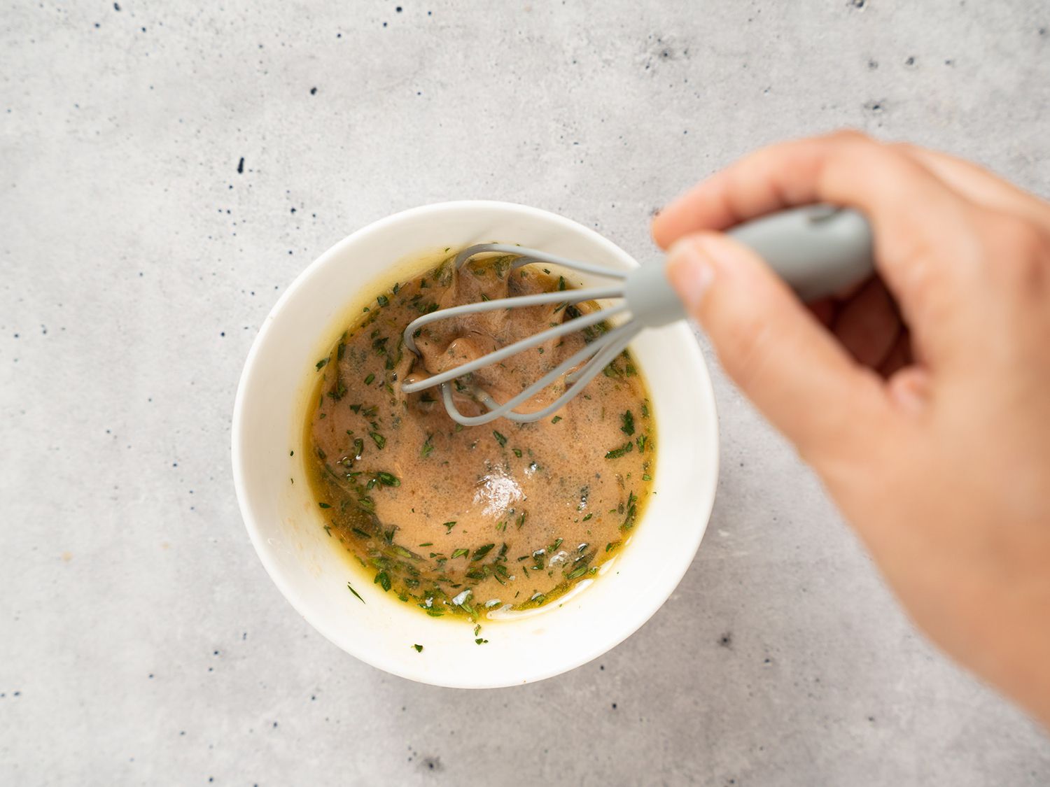 Whisking together vinaigrette in a small bowl for a delicata salad.