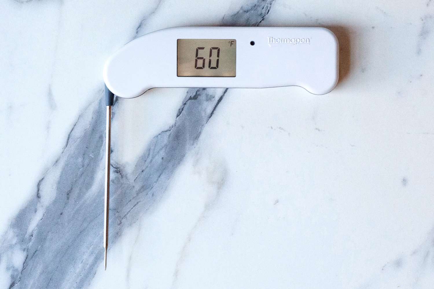 A white instant-read thermometer on a marble surface