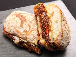 Cross-section view of a braised oxtail and Gruyère cheese sandwich split in half