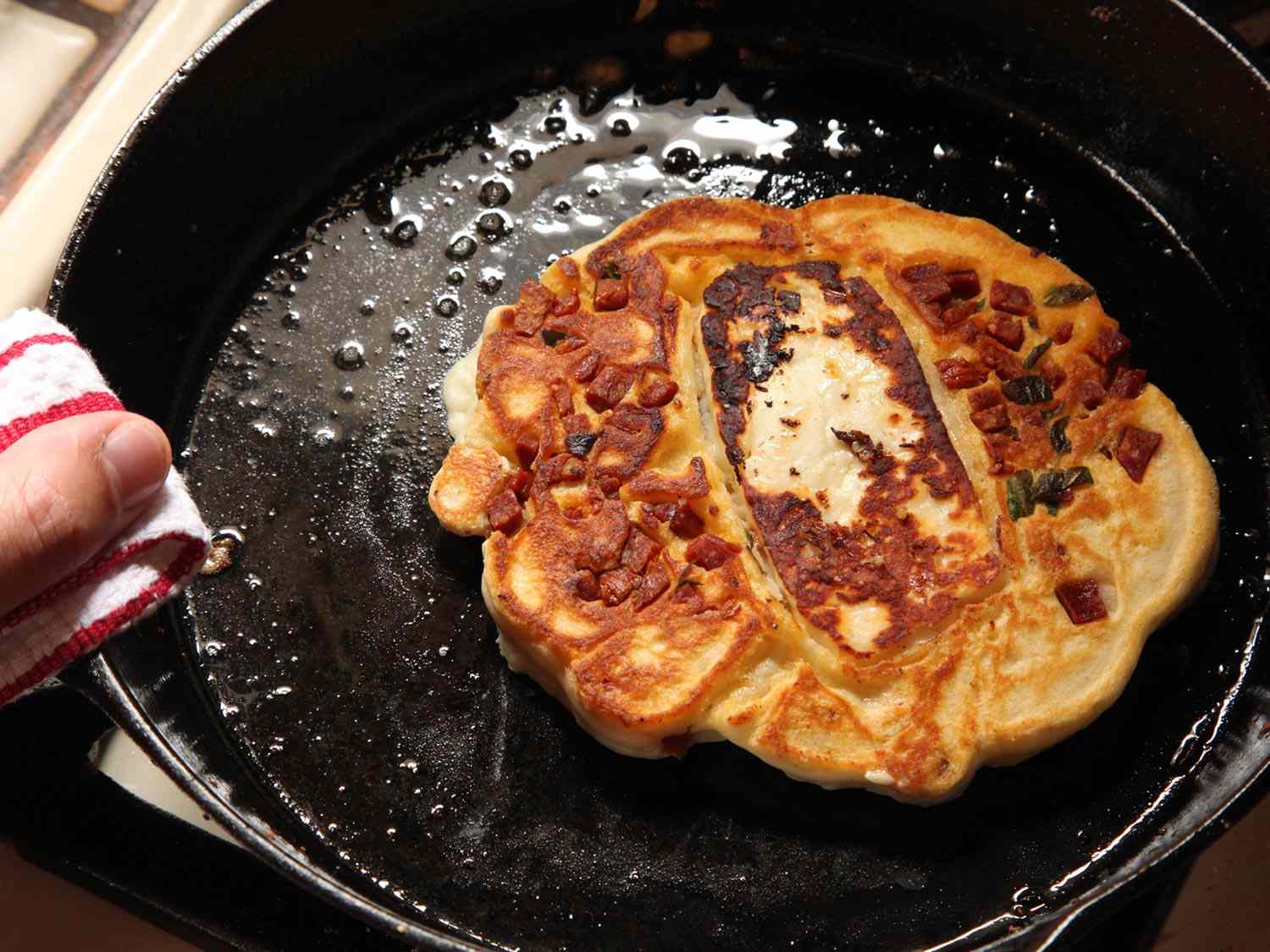 A savory pancake with chorizo and halloumi in a cast iron skillet