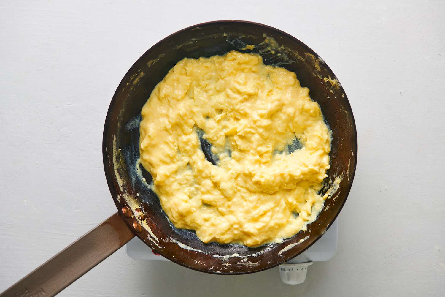 Very softly scrambled and creamy eggs inside skillet over medium-high heat