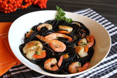 A bowl of black squid ink pasta with shrimp and scallops 