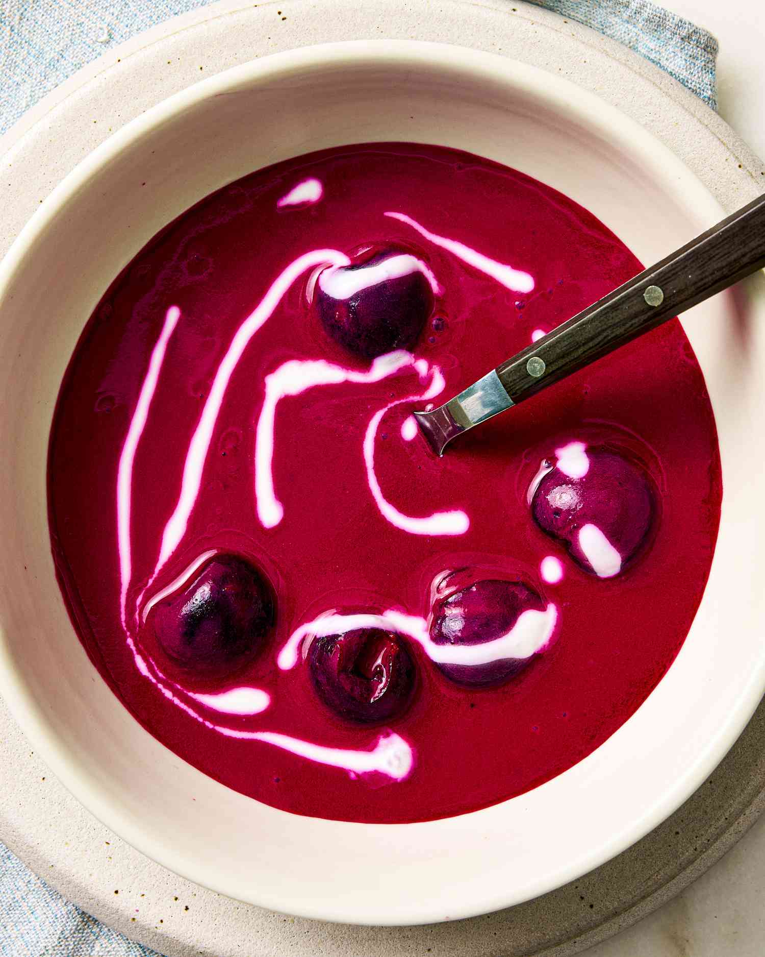 A bowl of beet and cherry soup with a swirl of sour cream 