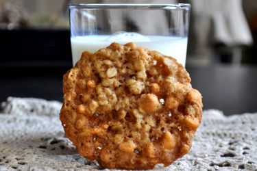 A coconut scotchy cookie, propped up against a glass of milk.