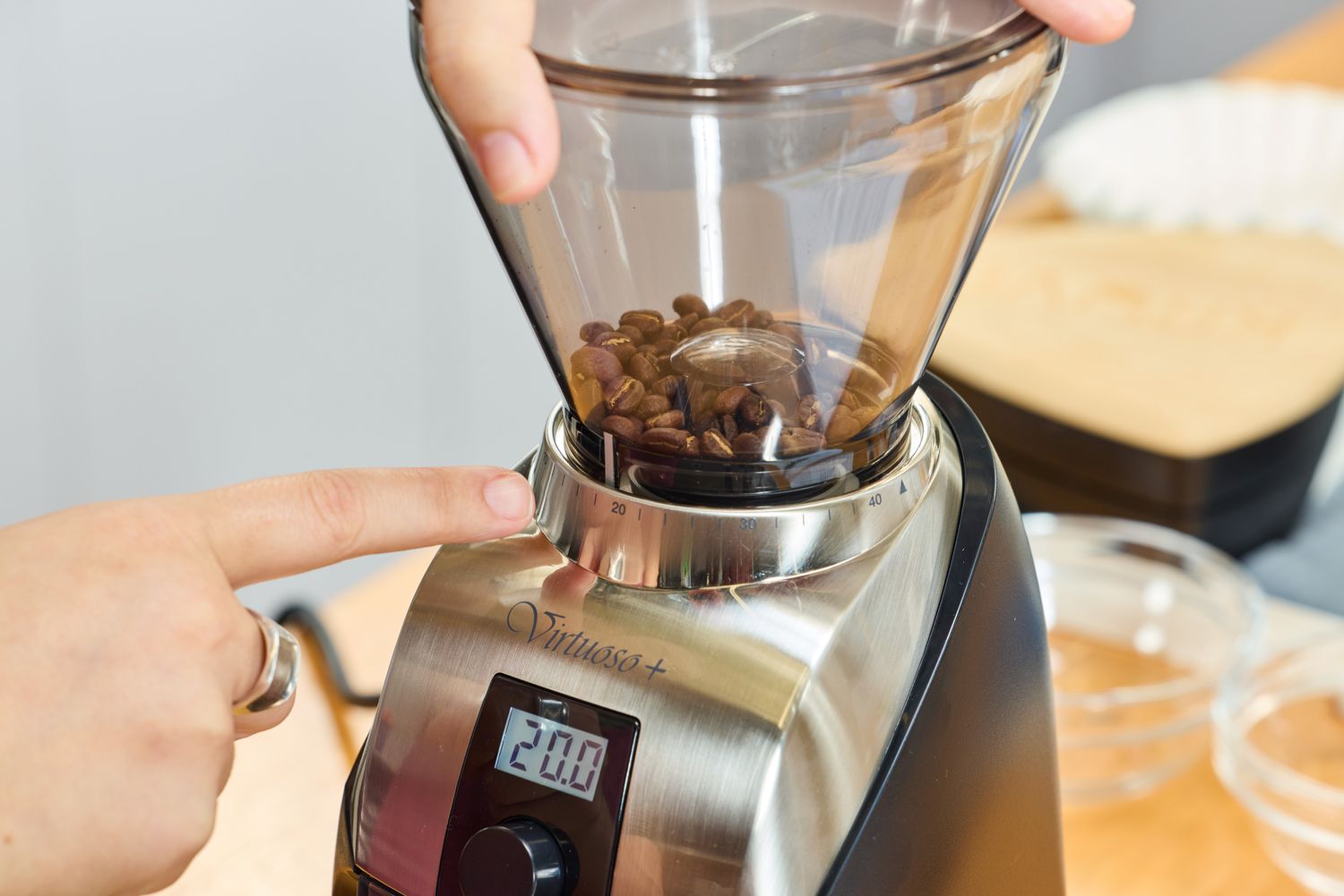 A person grinds coffee beans in the Baratza Virtuoso+ Conical Burr Coffee Grinder