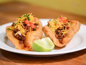 Two San Antonio-style puffy tacos garnished with lime