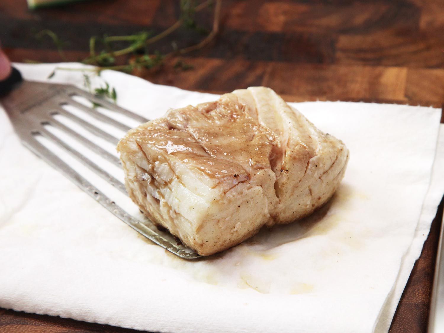 Placing a piece of cooked halibut on paper towels with a fish spatula. 