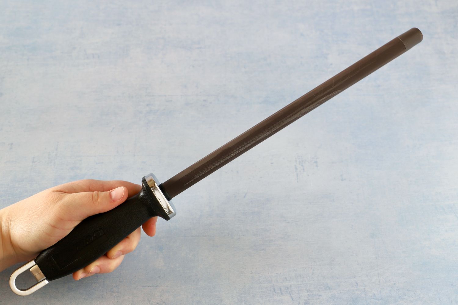 A hand holding a knife Mac ceramic sharpening steel rod