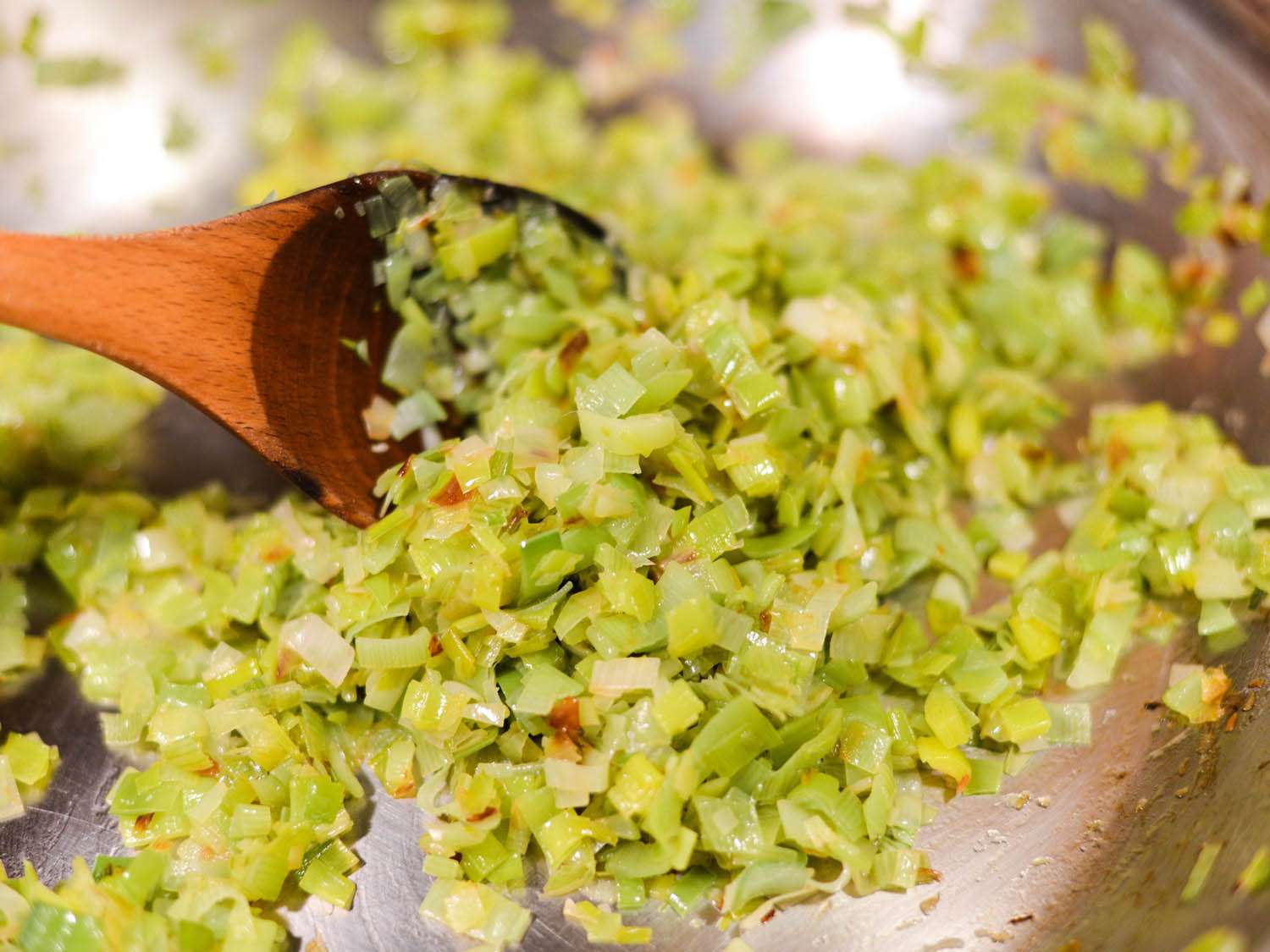 The finely chopped leek is cooked in a skillet.