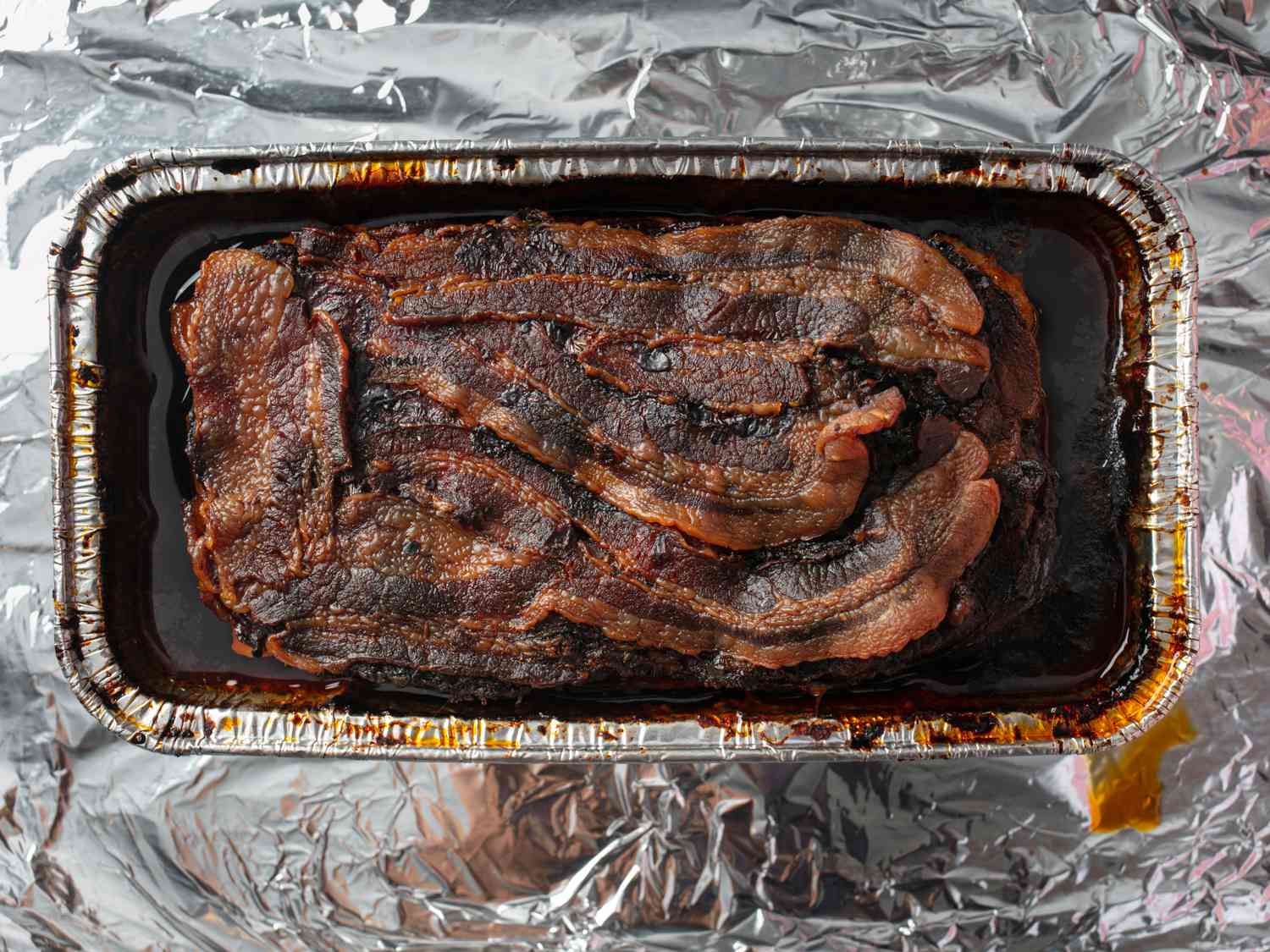 Loaf of cooked layered al pastor meat in aluminum pan