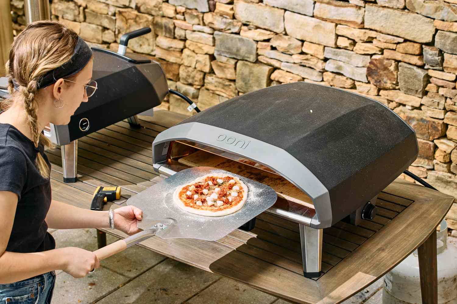 A person cooks a pizza in the Ooni Koda 2 Pro Gas-Powered Pizza Oven