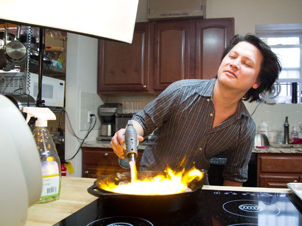 Kenji torching a steak in a cast iron pan with a propane torch