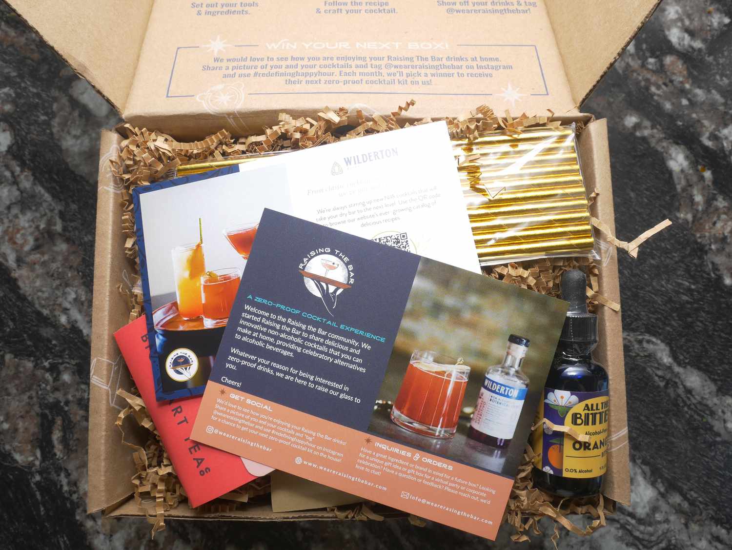 a box of cocktail supplies with several printouts on top of the supplies