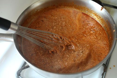 The chili mixture is whisked as it comes to a simmer.